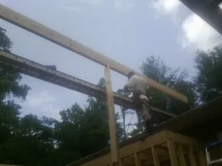 Carpenter setting a ridge beam over a new addition frame — Ice Dam Removal by Roofing Brothers in Round O
