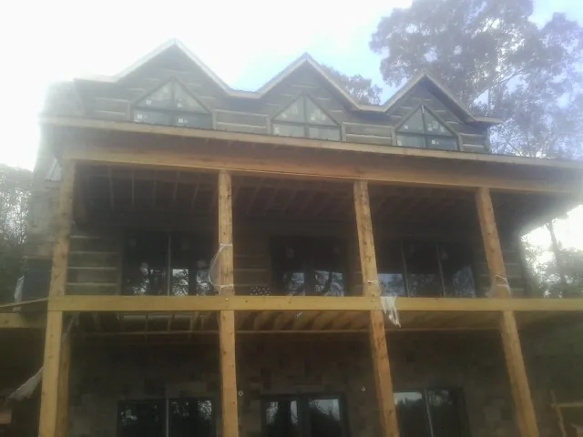 Dormers and porch framing on a large log home under construction — Roof Coating work by our crew in Round O