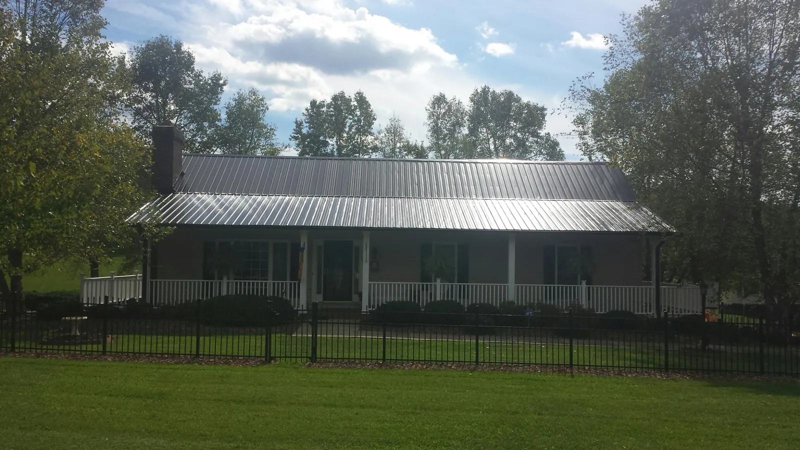 Gray metal roof on a brick ranch with a full width front porch — Gutter Guard Installation work by our crew in Round O