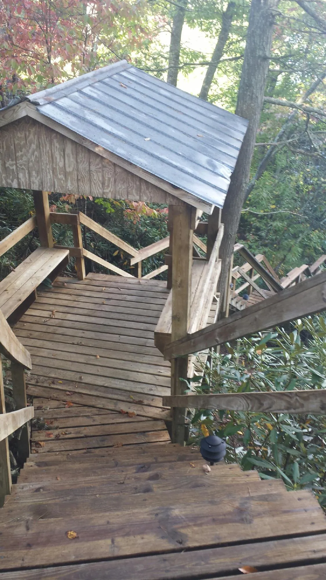Metal roofed shelter over wooden steps on a wooded walkway — Skylight Repair & Installation work by our crew in Round O